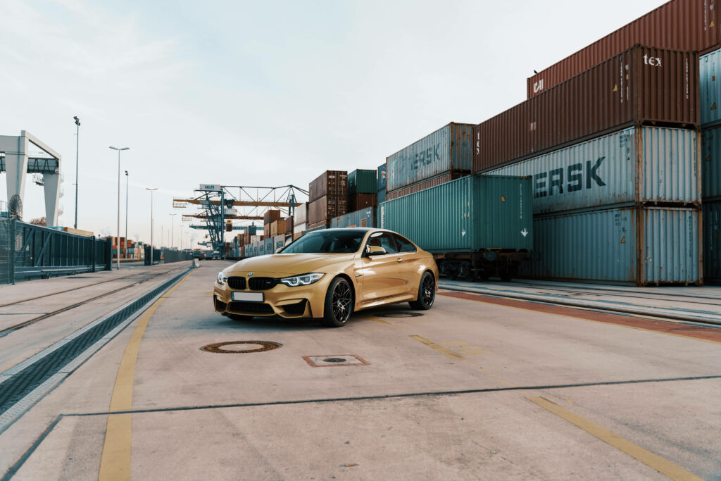 Seaport Serenity: Elegant Beige BMW Amidst Marine Container Scenery Wallpaper
