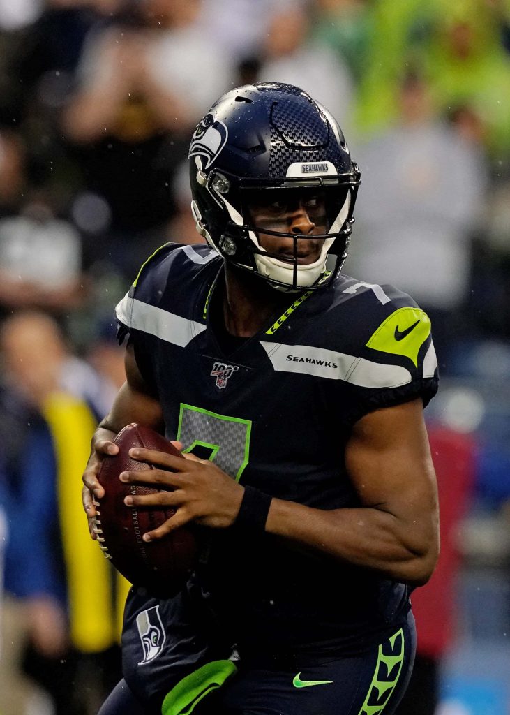 Seattle Seahawks quarterback Geno Smith in navy neon 7 jersey in action on field wallpaper background