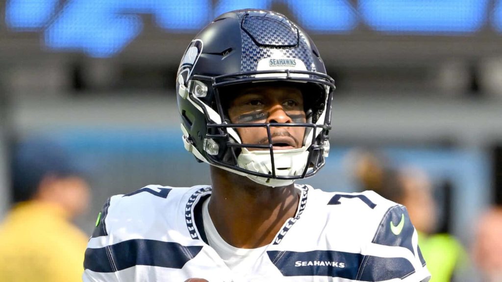 Seattle Seahawks quarterback Geno Smith focused in white uniform and dark helmet during game action Wallpaper