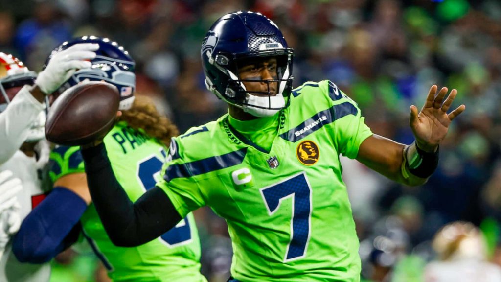 Seattle Seahawks quarterback Geno Smith mid-pass in neon green uniform NFL football action wallpaper