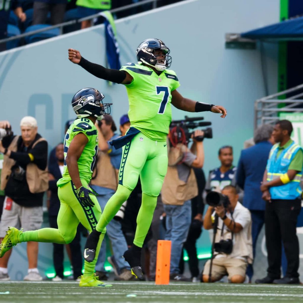 Seattle Seahawks quarterback Geno Smith in neon green jersey celebrating on game day field Wallpaper