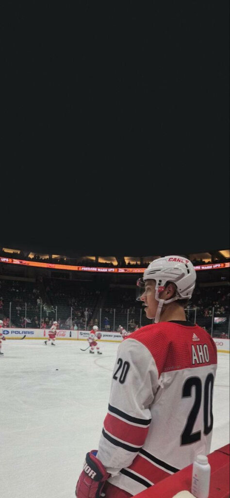 Sebastian Aho focused on ice in Carolina Hurricanes jersey during intense professional hockey game Wallpaper