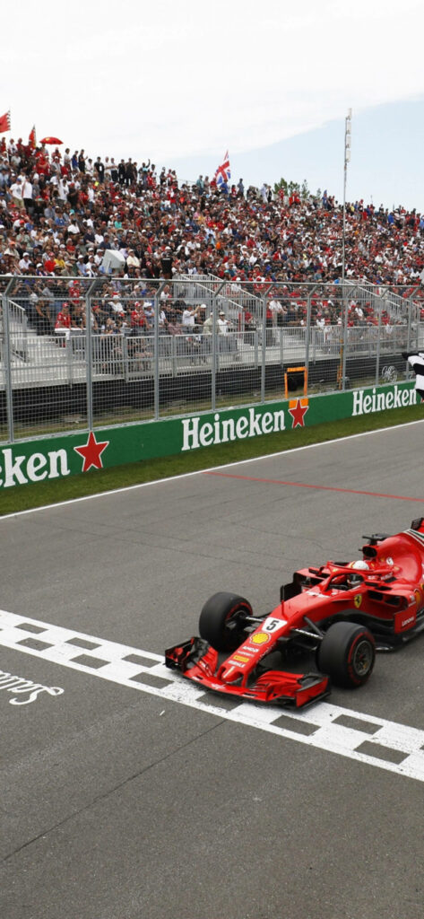 Sebastian Vettel Ferrari F1 car crossing finish line with cheering fans and Heineken banners Wallpaper