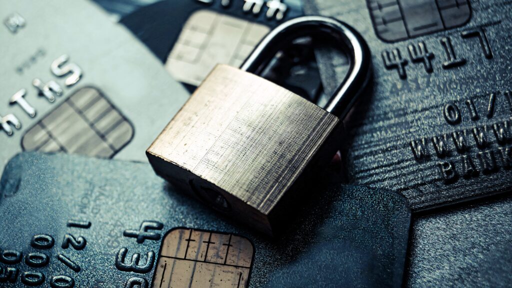 Metallic padlock on scattered credit cards symbolizing financial security and data protection close-up Wallpaper