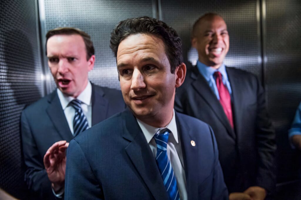 U S Senator Brian Schatz candid elevator photo with two men in suits bright modern politics background Wallpaper