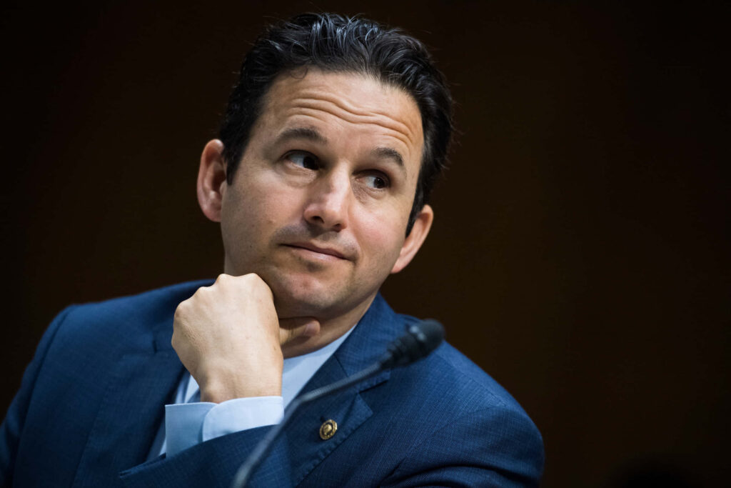Senator Brian Schatz thoughtful candid portrait in navy suit with blurred formal background wallpaper