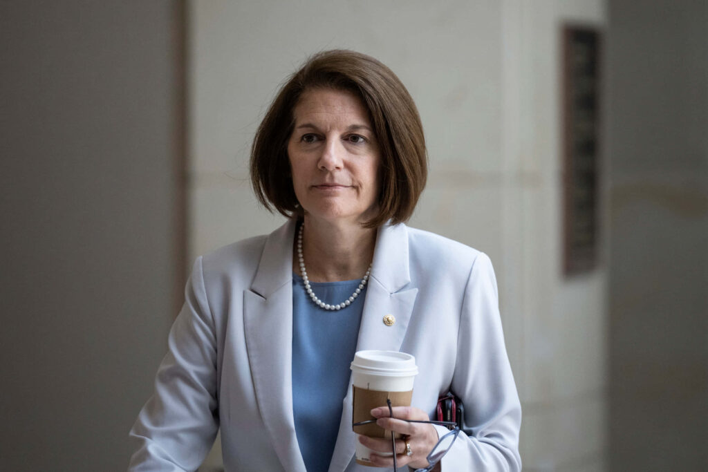 Senator Catherine Cortez Masto in light blazer with pearl necklace holding coffee cup professional setting Wallpaper