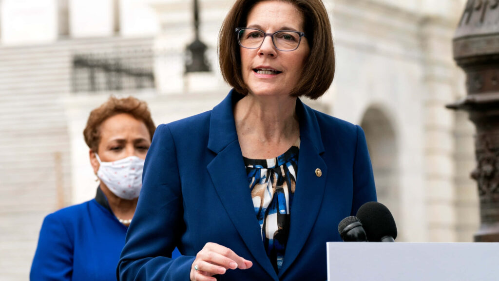 U.S. Senator Catherine Cortez Masto speaking outdoors at podium in blue blazer government buildings Wallpaper