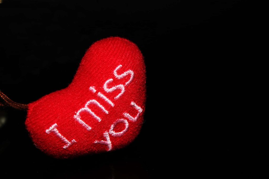 Macro photo of plush red heart embroidered with I miss you on black background romantic love Wallpaper