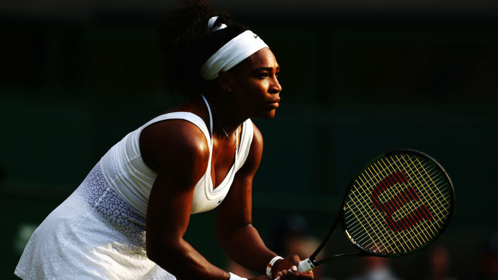 Serena Williams focused in defensive tennis stance showcasing athleticism and determination wallpaper