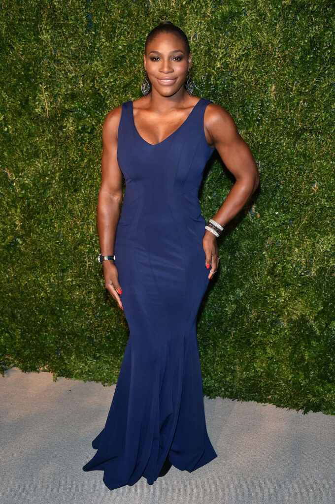 Serena Williams in elegant blue gown radiating strength against lush green wallpaper background