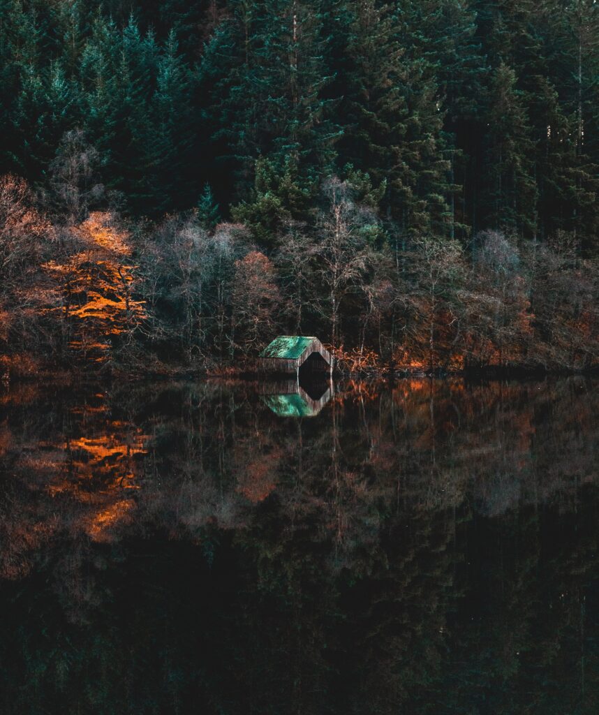Abandoned wooden jetty on still lake with evergreen forest and autumn foliage reflections wallpaper