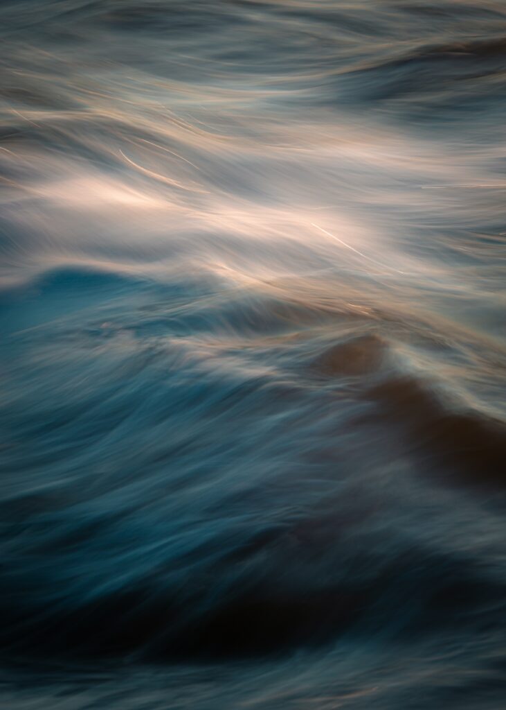 Abstract wallpaper of smooth flowing water waves in blue and gold long exposure background