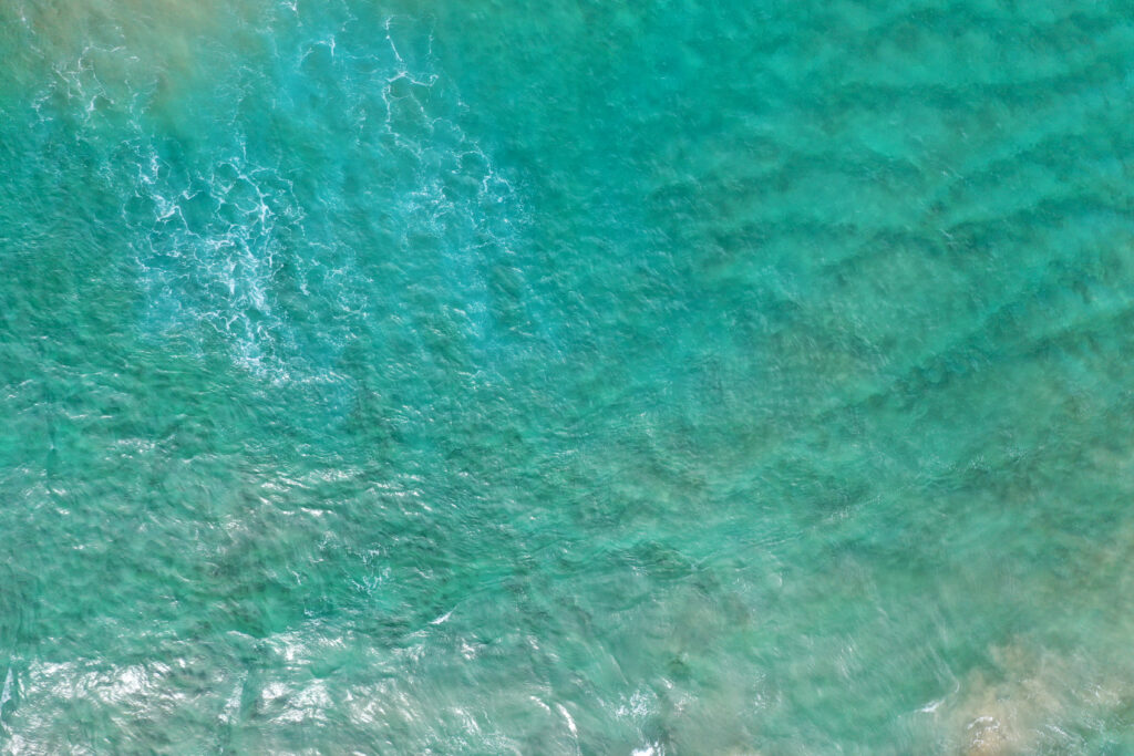 Aerial view of ocean waves with turquoise and blue shades creating a calming wallpaper background