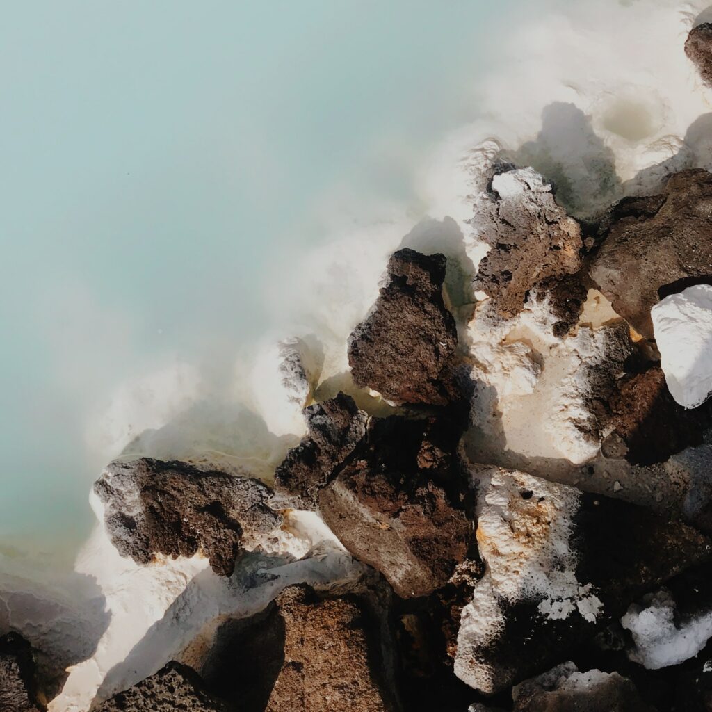 Aerial view of rugged rocks contrasting with milky blue water on a calm serene shore wallpaper
