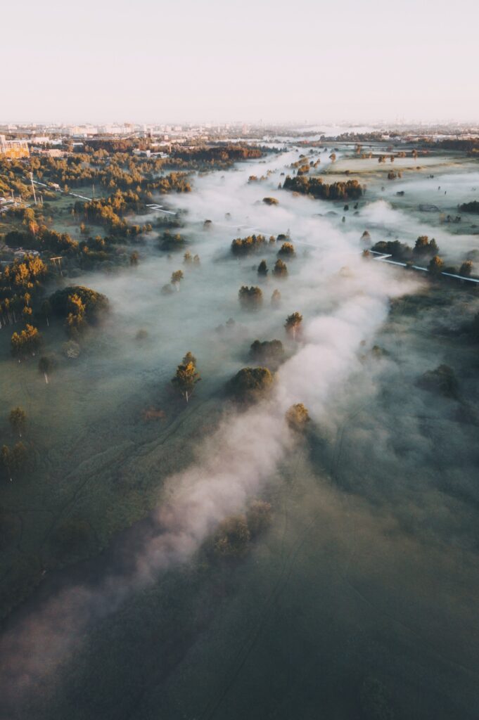 Serene Morning Fog Wallpaper: Lush Green Hills & Tranquil Town View