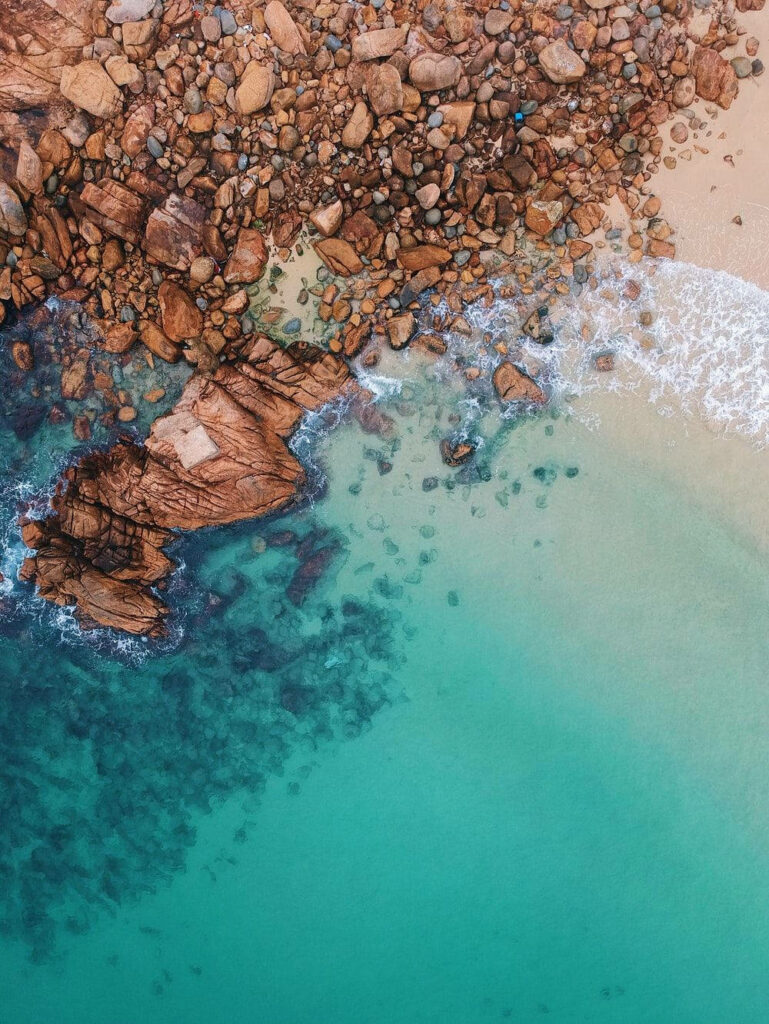 Stunning Aerial Rocky Coastline Wallpaper: Turquoise Sea & Earthy Tones