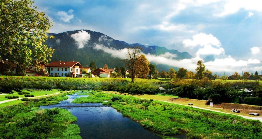 Serene Alpine farmhouse village with misty mountains river and vibrant green valley wallpaper
