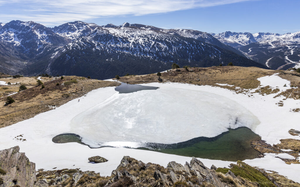 Serene alpine landscape wallpaper with rugged mountains frozen lake and gentle stone slopes