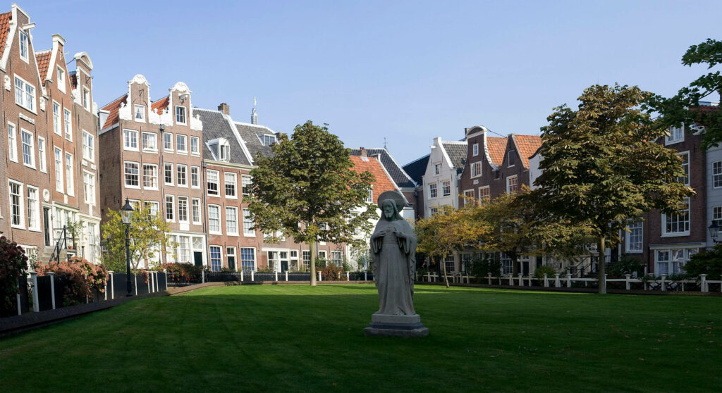 Serene Amsterdam Wallpaper: Beguine Statue Amid Lush Greenery