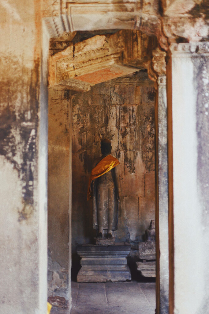 Serene Angkor Wat ruins with weathered statue in golden robe and ancient stone walls wallpaper