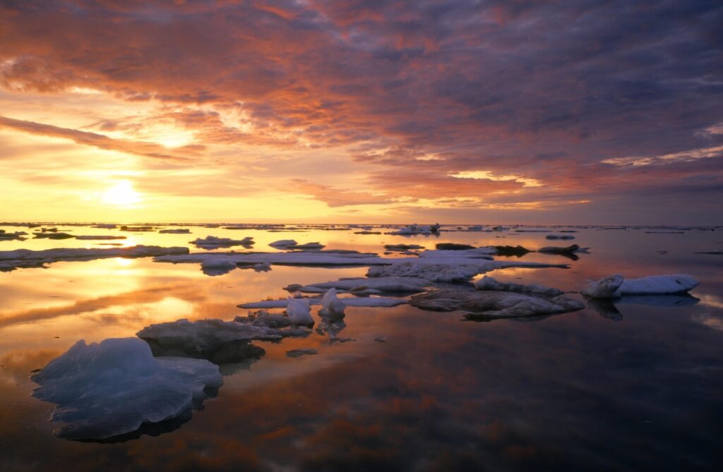 Serene Arctic sunset with layered drifting ice calm water vivid orange purple clouds reflection Wallpaper