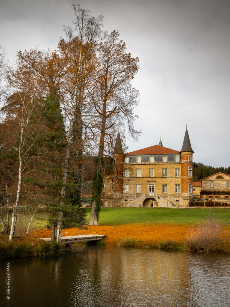 Classic castle by calm river surrounded by autumn trees and lush nature wallpaper background