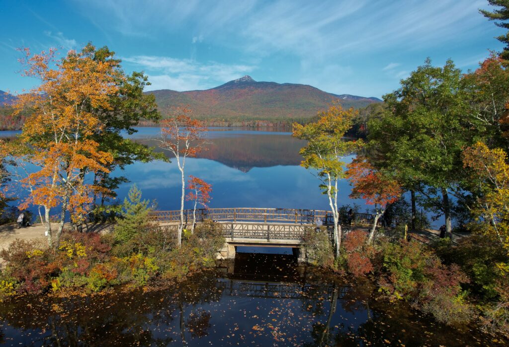 Serene autumn lake landscape with rustic wooden bridge colorful fall trees and clear blue sky wallpaper