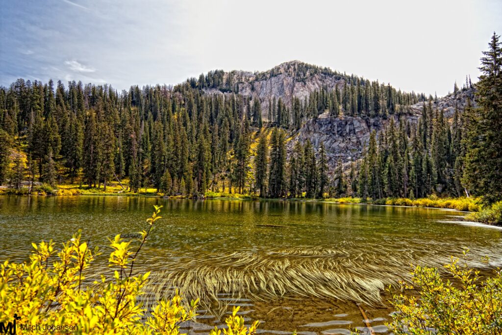 Serene autumn lake with vibrant fall foliage dense forest and towering mountains reflection wallpaper