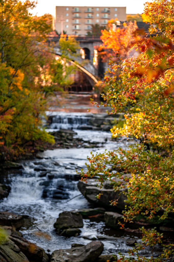 Serene autumn river landscape with colorful foliage smooth stones and distant stone bridge wallpaper