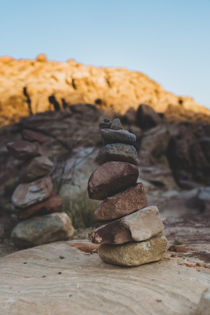 Stacked natural stones on rocky landscape with soft sunlight symbolizing harmony and stability background Wallpaper