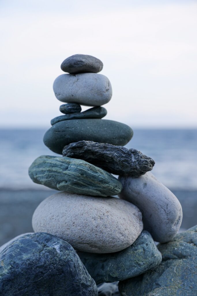 Serene wallpaper with balanced smooth gray green stones on calm seaside background for tranquility