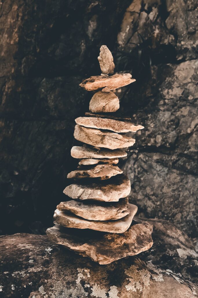Stacked flat stones balanced in cave with warm earth tones symbolizing harmony and tranquility Wallpaper