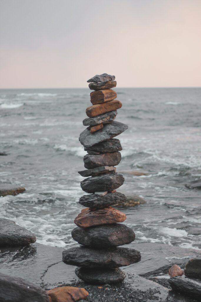Serene balanced stone stack with gentle sea waves minimalist wallpaper for calm relaxation
