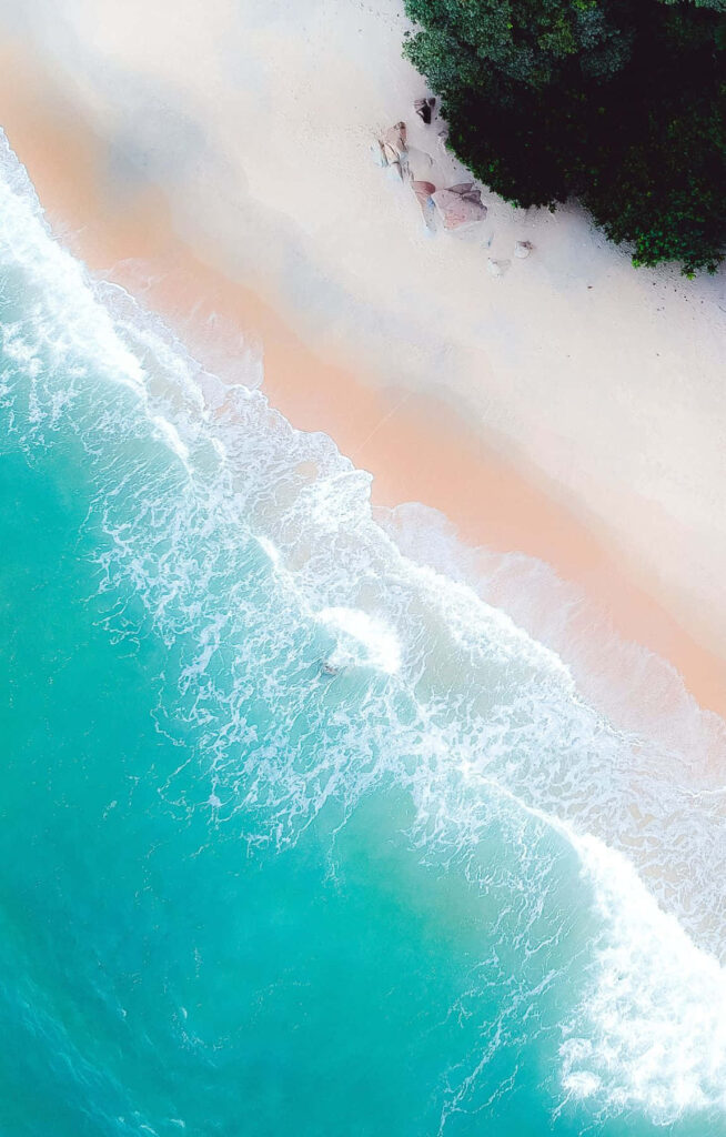 Serene Aerial Beach Scene with Turquoise Waves & Lush Greenery Wallpaper