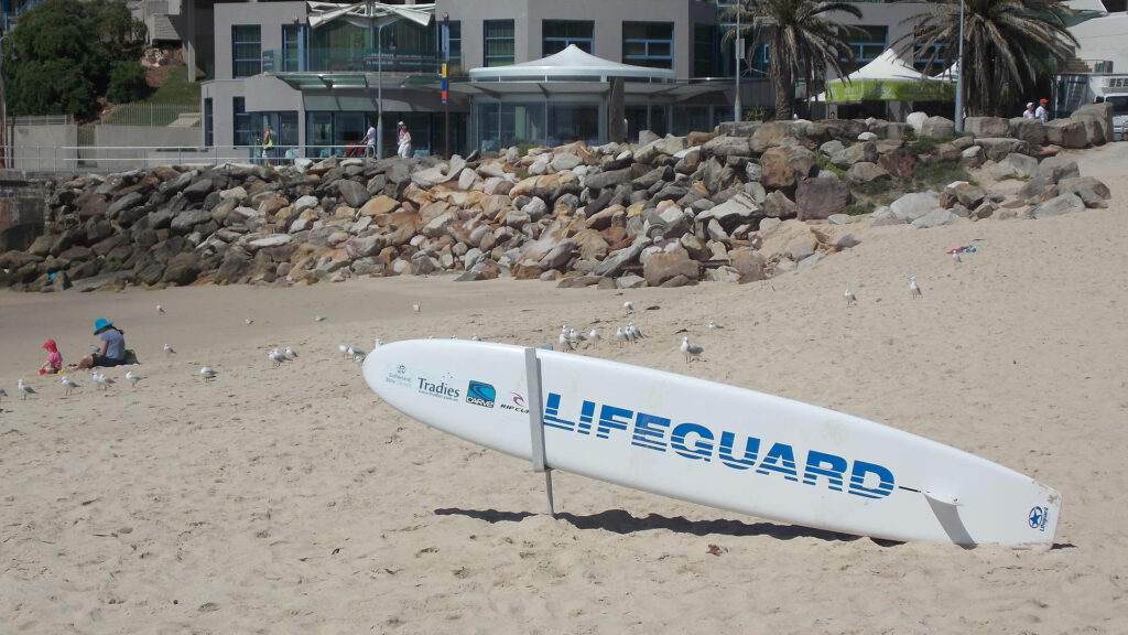 Serene Beach Scene Wallpaper with Lifeguard Surfboard