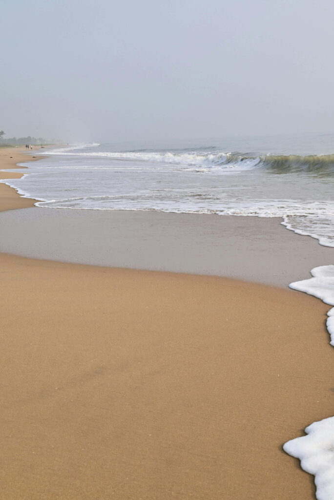 Serene Beach Wallpaper: Gentle Waves & Overcast Sky Background