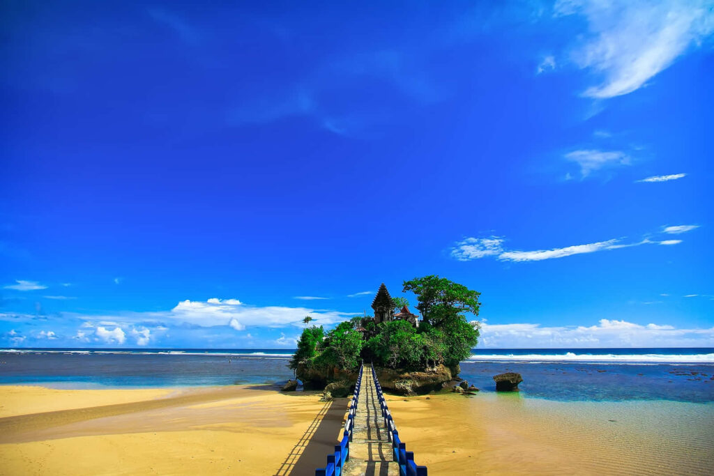 Serene Beach Scene: Sandy Shoreline & Vibrant Blue Sky Background Wallpaper