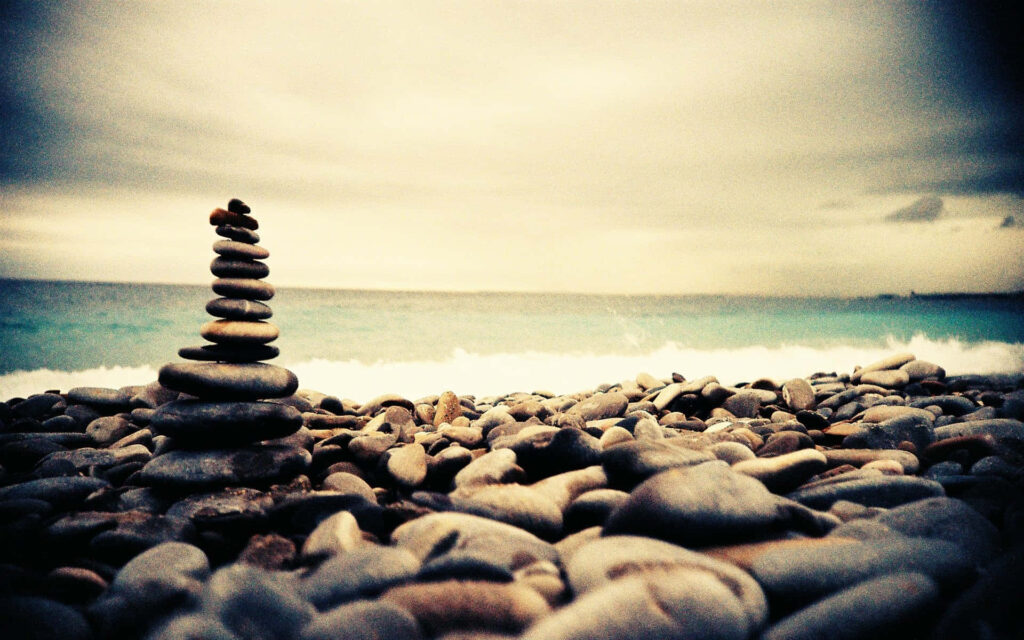 Zen Beach Scene: Serene Rocks on Tranquil Ocean Background Wallpaper
