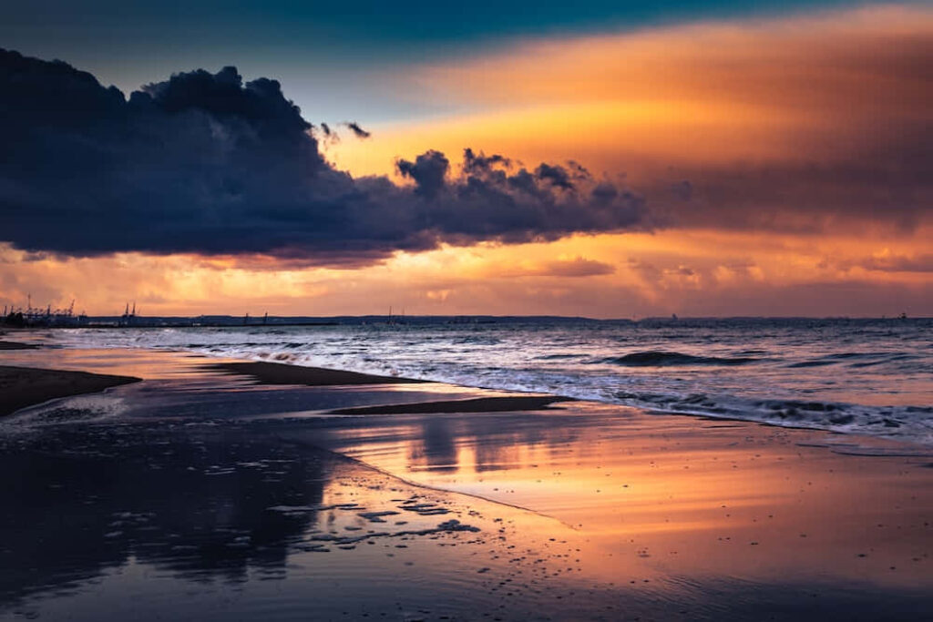 Tranquil Sunset Beach Wallpaper: Orange & Purple Sky Reflection