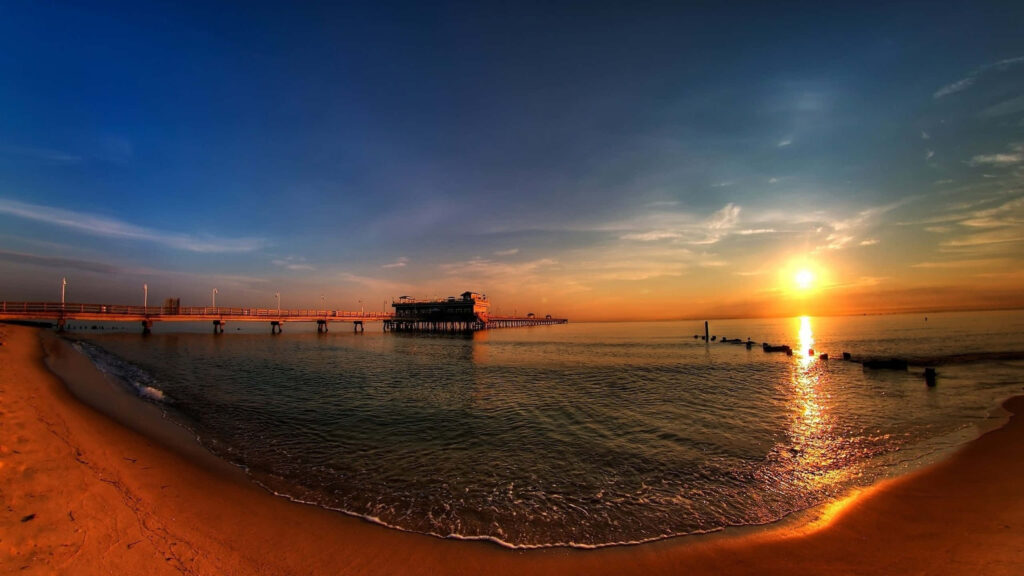 Serene Beach Sunset Desktop Background with Pier Reflection Wallpaper