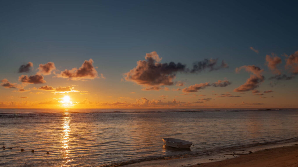Serene Sunset Beach Wallpaper with Tranquil Boat Reflection