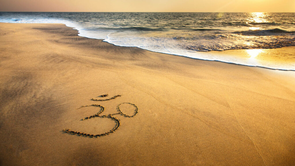 Serene Beach Sunset Wallpaper with Om Symbol in Sand - Peaceful Background