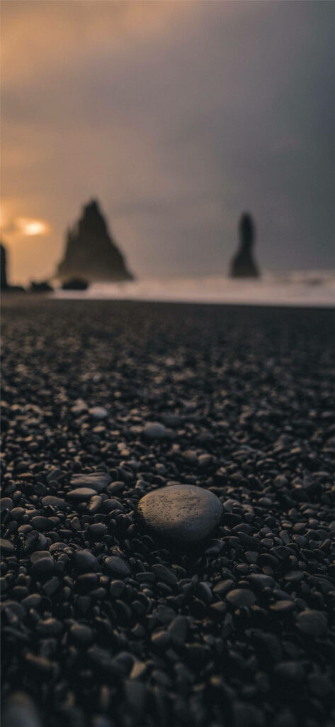 Tranquil Beach Sunset Wallpaper with Pebbles & Silhouetted Rocks