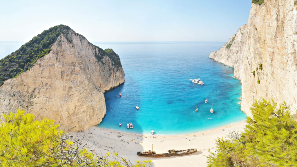 Serene Beach Wallpaper: Stunning Cliffs & Intriguing Shipwreck Backdrop