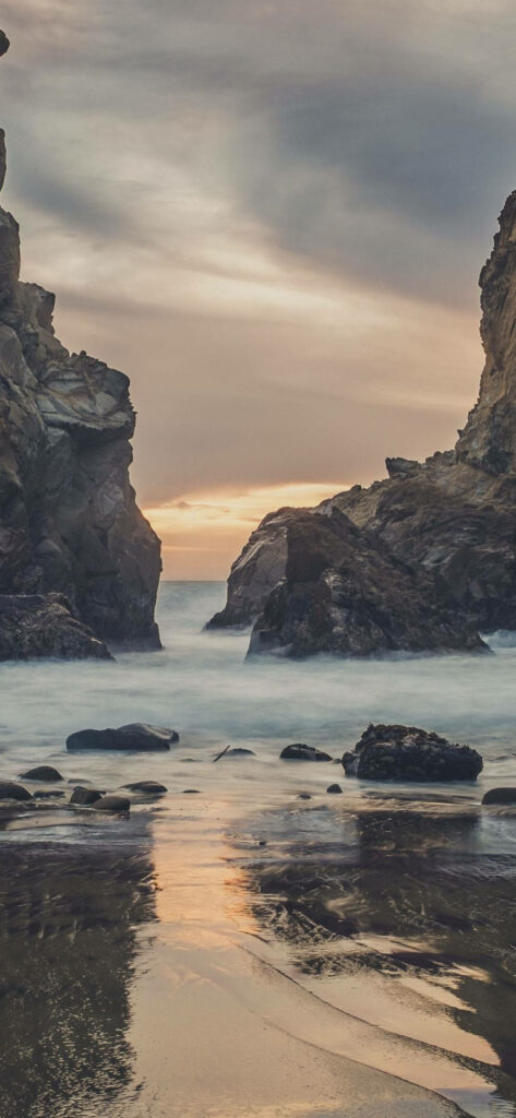 Tranquil Beach Wallpaper: Gray Rocks & Cloudy Sky for iPhone Background