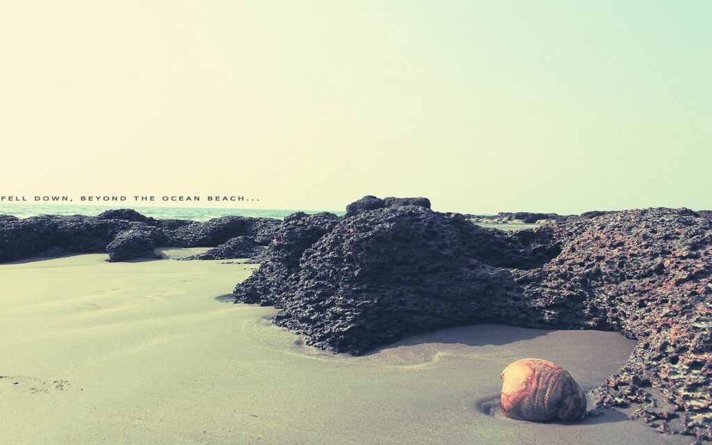 Serene beach wallpaper with soft sand rugged reefs gentle ocean clear sky warm colors
