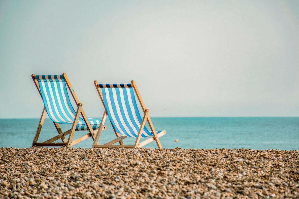 Tranquil Beach Scene Wallpaper: Striped Chairs & Calm Ocean Serenity