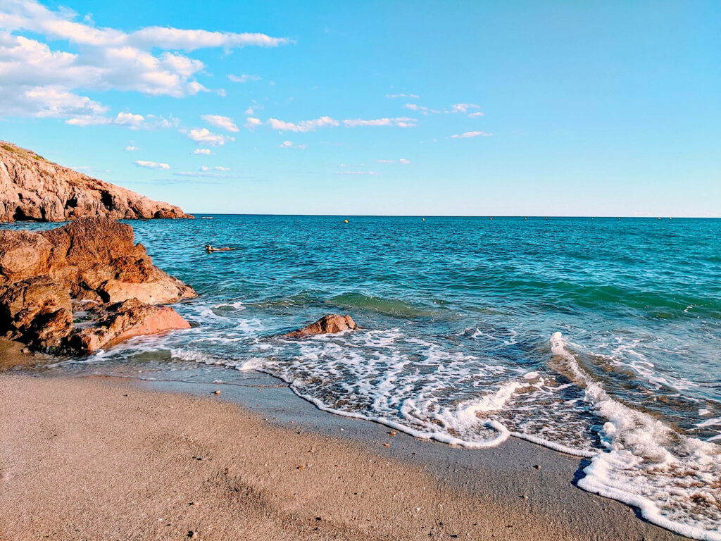 Serene Coastal Beach Wallpaper: Gentle Waves & Rugged Rocks Background