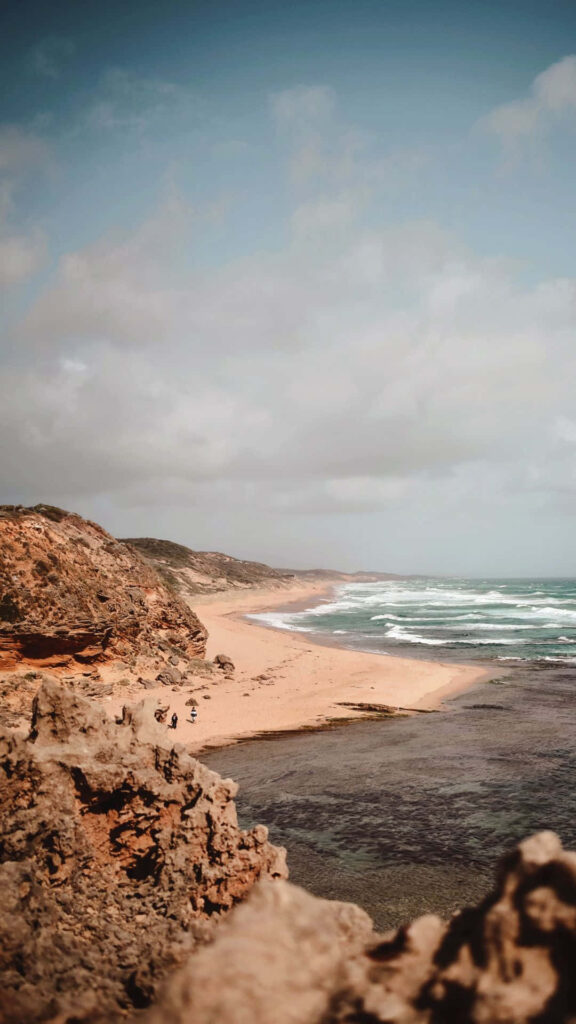 Tranquil Beach Scene Wallpaper: Serene Waves & Rocky Cliffs